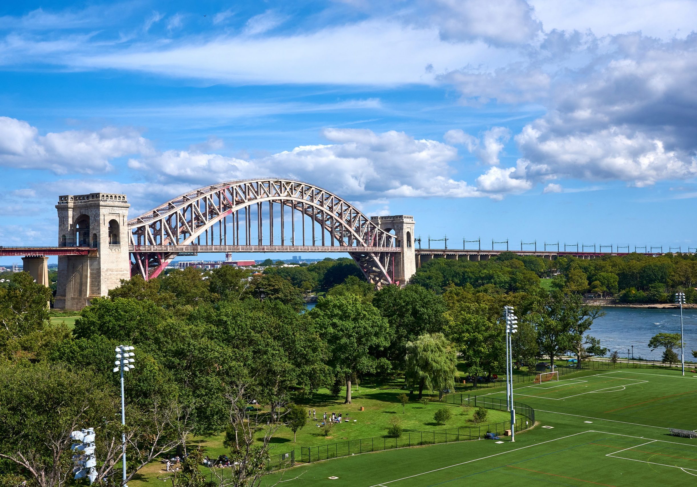 Hell Gate Bridge, with the fields of Wards Island and Randalls Island Park in the foreground. Hell Gate Bridge is a metal arch railroad bridge, spanning the East River, built in 1916.